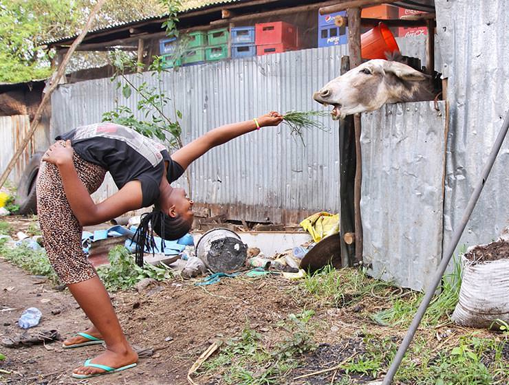 Arba Minch Circus contortionist backbending to feed the donkey with grass as a part of fundraising project Circus of Postcards, in Arba Minch, Ethiopia, photo by Ivan Kralj