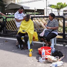 Photograph of a street barber shaving bald one of the Thaipusam pilgrims, while his wife obseres, photo by Ivan Kralj