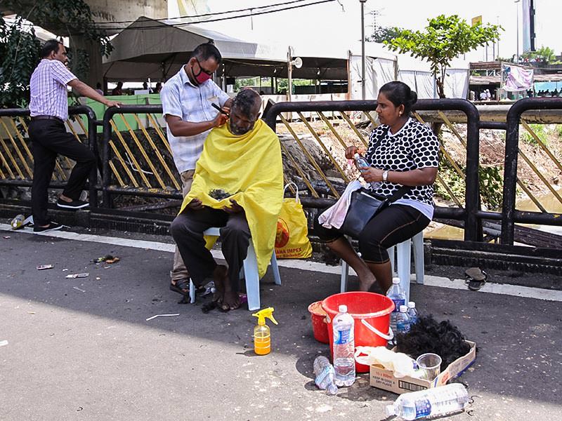 Photograph of a street barber shaving bald one of the Thaipusam pilgrims, while his wife obseres, photo by Ivan Kralj