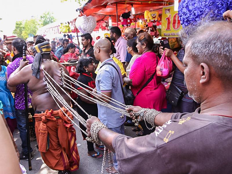 Photograph of a man pulling the chains attached to the hooks piercing the skin of the back of the other man, an extreme ritual at Thaipusam festival, photo by Ivan Kralj