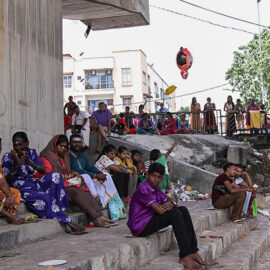 Photograph of Thaipusam pilgrims resting in the shade at the river bank at Thaipusam festival
