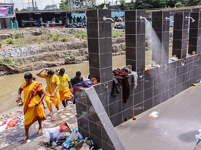 Photograph of a family dressed in vividly yellow dresses leaving the river where they had a ritual bath and left offerings to gods at Thaipusam, photo by Ivan Kralj