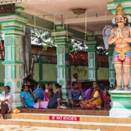 Photograph of Thaipusam pilgrims resting at one of the Batu Caves temple, sitting on the floor, with the sign "No shoes", photo by Ivan Kralj