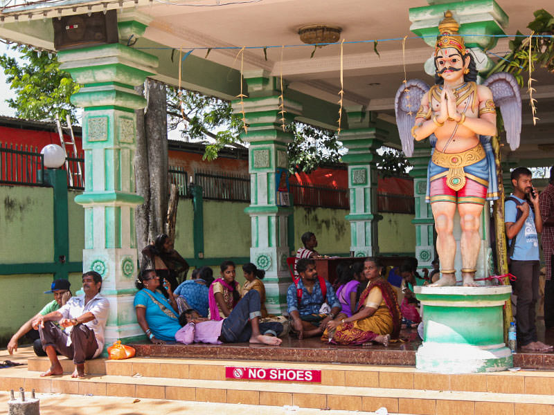 Photograph of Thaipusam pilgrims resting at one of the Batu Caves temple, sitting on the floor, with the sign "No shoes", photo by Ivan Kralj