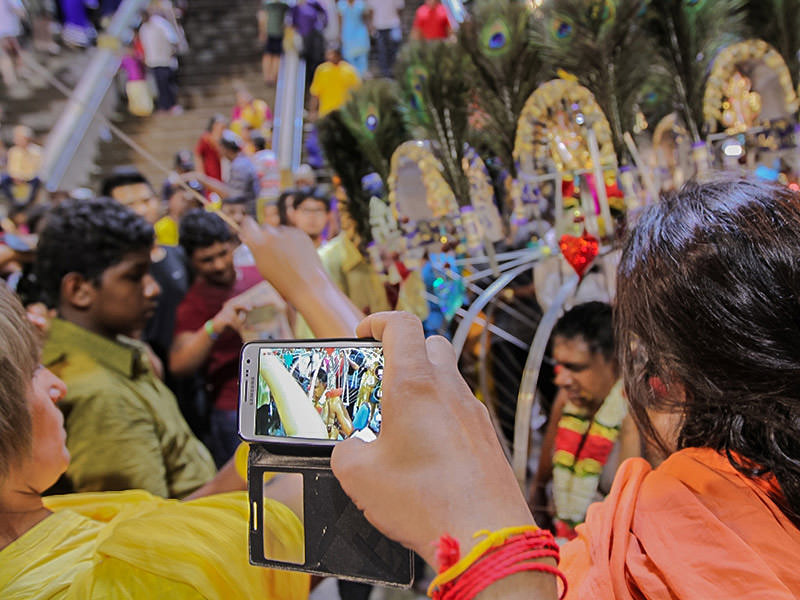 Photograph of tourists photographing the Kavadi bearer removing his skewers and piercings, photo by Ivan Kralj