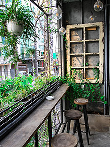 Balcony at The Laban hotel in Saigon, with green plants, light bulbs and rustical wooden details