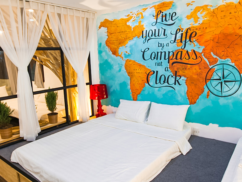 The photo of a bed in the room of The Laban hotel, with "Live your Life by a Compass, not a Clock" message on the wall