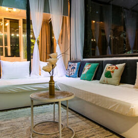 The photo of a white couch in The Laban hotel room, with vividly coloured pillows and big windows, photo by Ivan Kralj