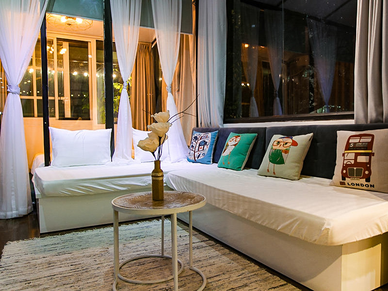 The photo of a white couch in The Laban hotel room, with vividly coloured pillows and big windows, photo by Ivan Kralj