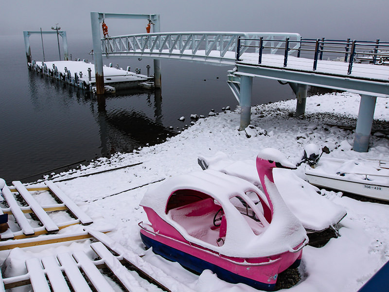 Snow-covered swan-shaped pedal boats at the shore of the Chuzenji Lake, Japan, photo by Ivan Kralj
