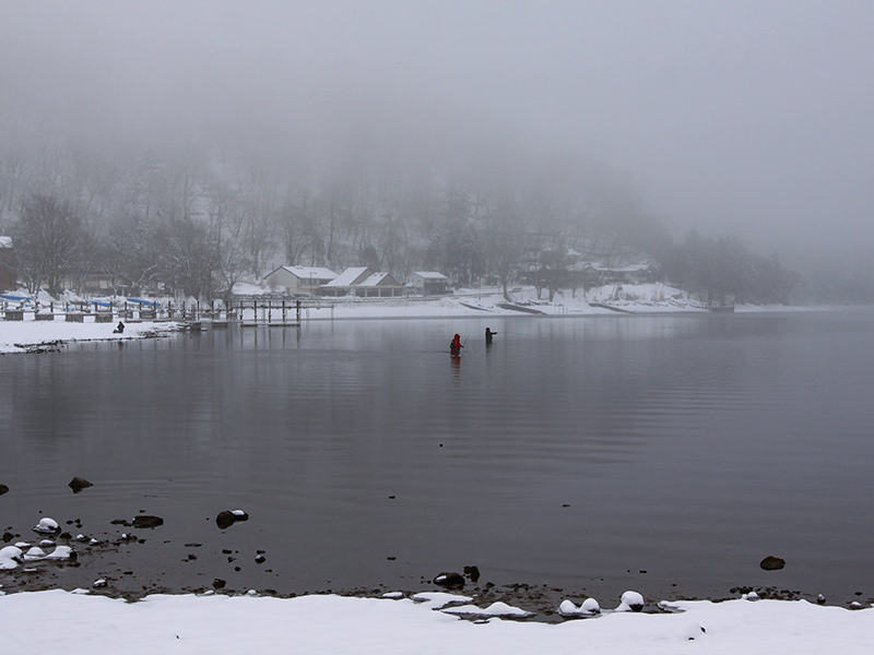 Two fishermen standing waist-deep in the snow-surrounded Chuzenji Lake, close to Nikko, Japan, photo by Ivan Kralj
