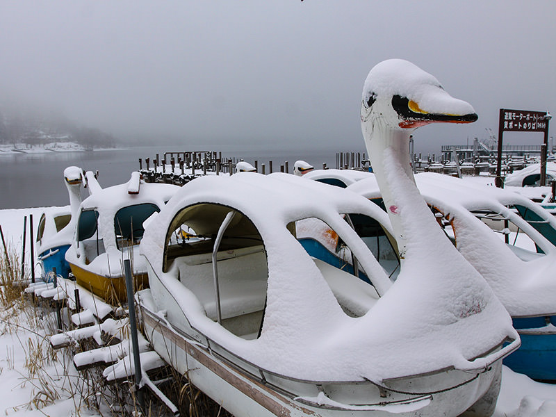 Snow-covered swan-shaped pedal boats at the shore of the Chuzenji Lake, Japan, photo by Ivan Kralj