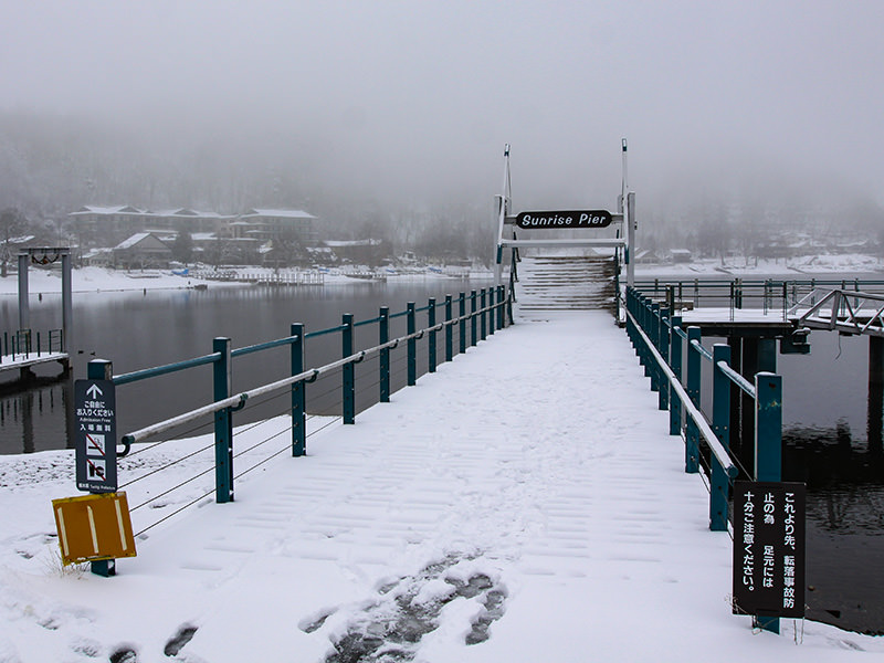 Snow-covered pier at Chuzenji Lake, Japan. The sign with somewhat ironic name "Sunrise Pier" is visible. Photo by Ivan Kralj