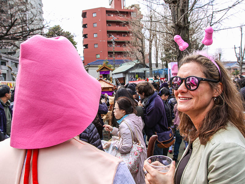 A man wearing a pink penis-head shaped hat and a woman wearing penis-shaped hair decoration at Kanamara Matsuru, festival of the iron penis, in Kawasaki, Japan, photo by Ivan Kralj