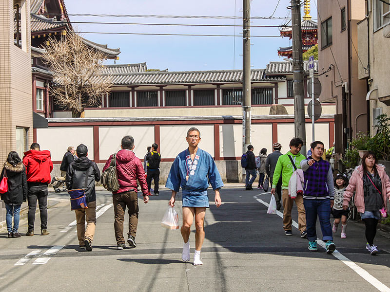A man dressed up in typically short kimono, no trousers, is walking down the street of Kawasaki, Japan, for Kanamara Matsuri, the festival of iron penis, photo by Ivan Kralj