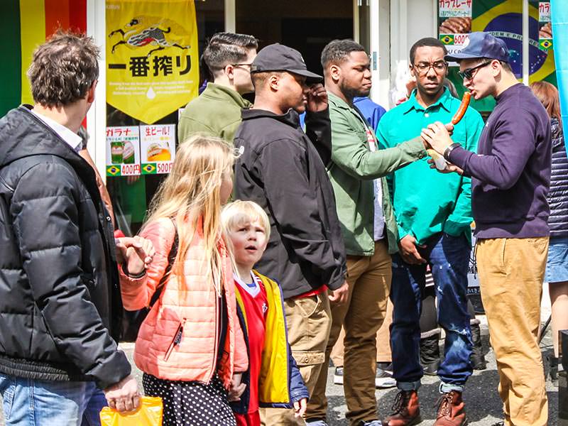 Three young men licking penis-shaped lollipops in Kawasaki, Japan, during the Kanamara Matsuri, festival of the iron penis, photo by Ivan Kralj