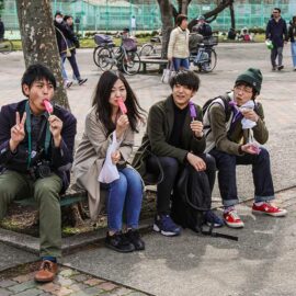 Friends licking penis-shaped lollipops in the park in Kawasaki, Japan, during the Kanamara Matsuri, festival of the iron penis, photo by Ivan Kralj