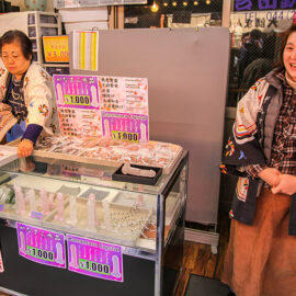 Woman smiling at the market, selling penis-shaped crystals for 1000 yen, at Kanamara Matsuru, festival of the iron penis, in Kawasaki, Japan, photo by Ivan Kralj