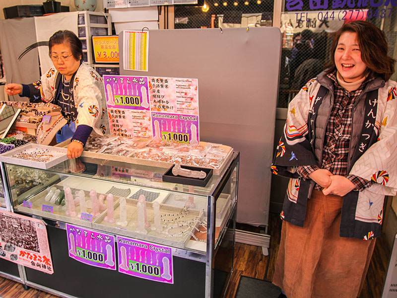 Woman smiling at the market, selling penis-shaped crystals for 1000 yen, at Kanamara Matsuru, festival of the iron penis, in Kawasaki, Japan, photo by Ivan Kralj