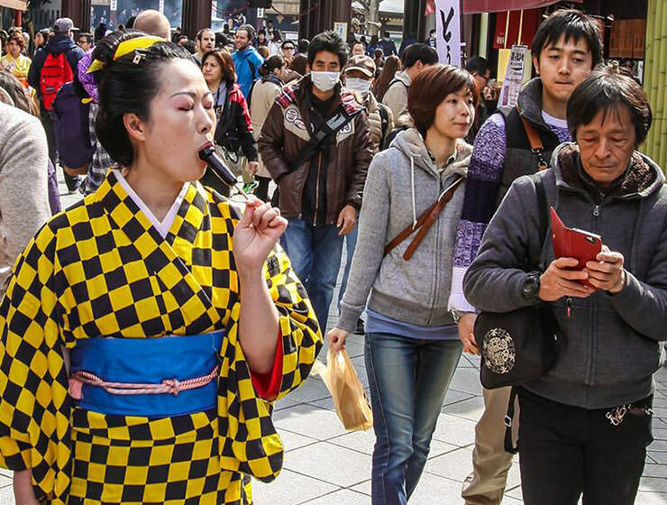 The lady in eccentric yellow-black checkered kimono is licking a penis-shaped lollipop in the street at Kanamara Matsuru, festival of the iron penis, in Kawasaki, Japan, photo by Ivan Kralj
