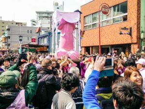 People on the streets of Kawasaki taking pictures and greeting the giant pink penis being carried around as a portable shrine at Kanamara Matsuri, Japanese penis festival, photo by Mladen Koncar