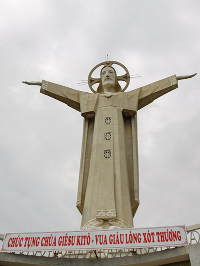 Vietnamese Jesus statue, Christ the King in Vung Tau, stretching his arms in front of the dark clouds, photo by Ivan Kralj