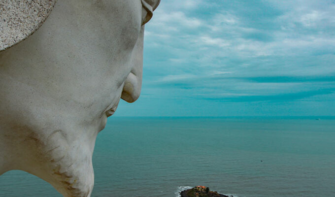 The head of Christ the King statue in Vung Tau, Vietnam, overlooking the South China Sea, with a little island, and dark clouds in the sky, photo by Ivan Kralj