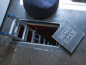 Entrance to the basement of the ARTnSHELTER hostel in Tokyo, Japan, open hole with ladders coming out, and cover saying "Do not open", photo by Ivan Kralj.