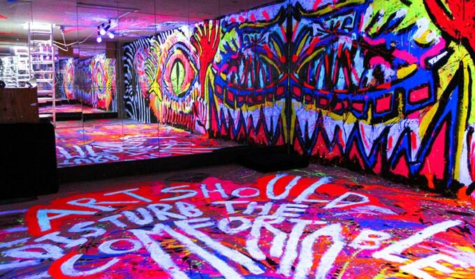 One of the most colorful rooms in hostels in Tokyo, Japan: basement in ARTnSHELTER hostel with walls painted in fluorescent colors, and "Art should disturb the comfortable" message on the floor, by Singaporean street artist Zon, photo by Ivan Kralj