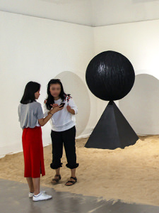 The girl checking how did she turn out on the photograph for which she was posing in the middle of Monica Hapsari's artwork "Antara", sitting in the sand as if on a beach, at Galeri Nasional Indonesia, Jakarta, EXI(S)T - Tomorrow As We Know It exhibition, photo by Ivan Kralj