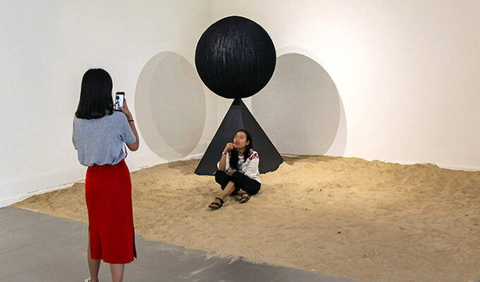Art of making selfies: The girl posing for a photograph in the middle of Monica Hapsari's artwork "Antara", sitting in the sand as if on a beach, at Galeri Nasional Indonesia, Jakarta, EXI(S)T - Tomorrow As We Know It exhibition, photo by Ivan Kralj