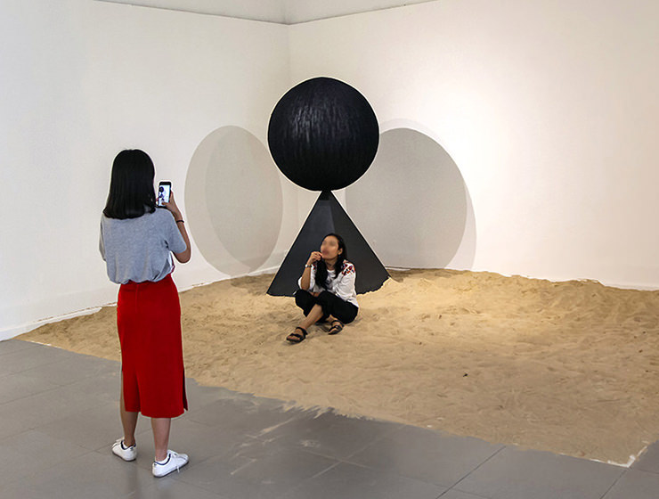 Art of making selfies: The girl posing for a photograph in the middle of Monica Hapsari's artwork "Antara", sitting in the sand as if on a beach, at Galeri Nasional Indonesia, Jakarta, EXI(S)T - Tomorrow As We Know It exhibition, photo by Ivan Kralj
