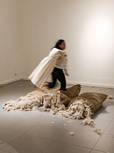 The girl visitor of Galeri National Indonesia in Jakarta, running over the jute sacks, while carrying the dress on a hanger in hands, all elements of Ratu R. Saraswati's artwork "I Beg I Promise". This shocking intervention in the art installation is explained by the girl's intention to be photographed for social media, at the EXI(S)T - Tomorrow As We Know It exhibition, photo by Ivan Kralj.