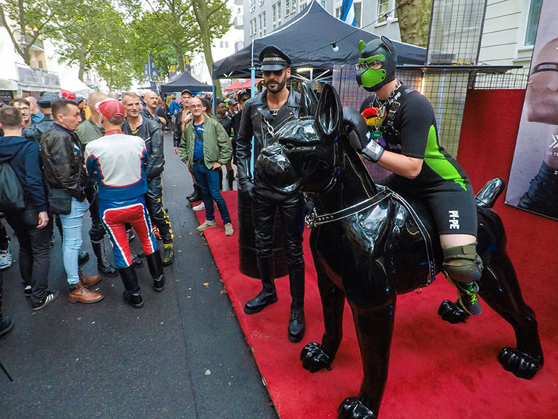 Human puppy riding the sculpture of a boxer dog, posing for a photo at Folsom Europe Street Fair, the biggest European gay fetish event, in Berlin, Germany, photo by Ivan Kralj