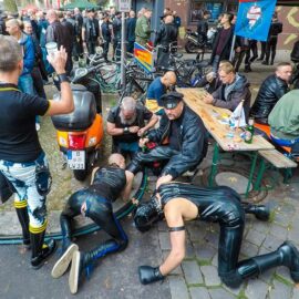 Two slaves are licking the boots of their master while he is enjoying his beer at Folsom Europe Street Fair, the biggest European gay fetish event, in Berlin, Germany, photo by Ivan Kralj