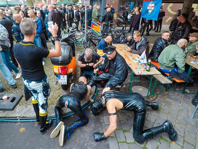 Two slaves are licking the boots of their master while he is enjoying his beer at Folsom Europe Street Fair, the biggest European gay fetish event, in Berlin, Germany, photo by Ivan Kralj