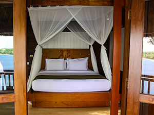 Bed in one of the Beach Villas, with sea reflecting in the windows, at The Menjangan Resort, one of the answers to where to stay in Bali, Indonesia, photo by Ivan Kralj