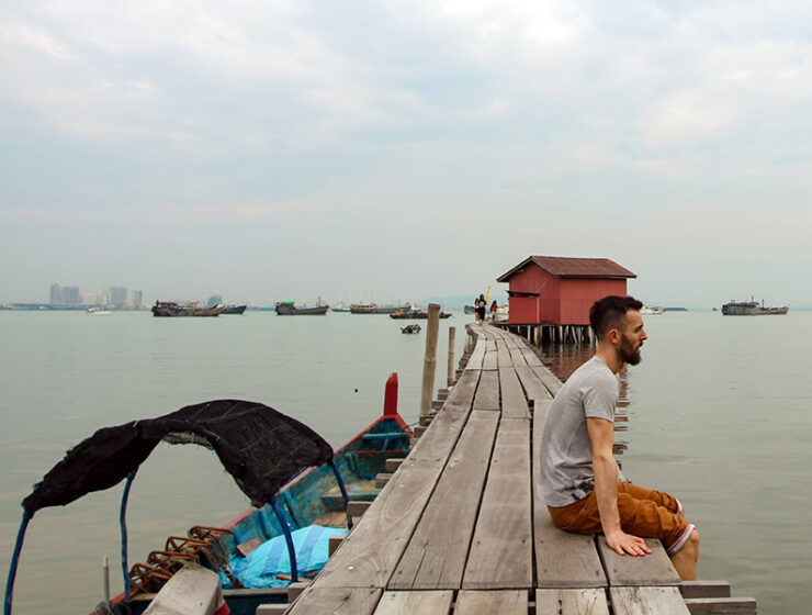 Pipeaway blogger Ivan Kralj sitting on one of the jetties in Georgetown, Penang Island, Malaysia, boats lining up on the horizon, photo by Weile Ng