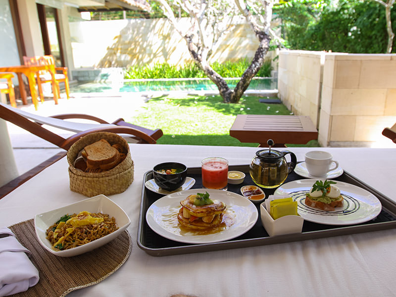 Bali honeymoon breakfast - a variety of food served at the daybed in the privacy of one of the villa pavilions, with swimming pool in the background, in the Balé resort, in Nusa Dua, in Bali, Indonesia, photo by Ivan Kralj