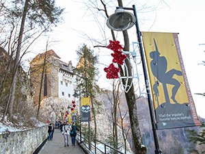 Pathway towards the Bran Castle, also known as Dracula Castle, with poster of impaled men silhouettes, in Transylvania, Romania, photo by Ivan Kralj