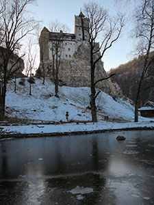 Bran Castle, also known as Dracula Castle, on the snow-covered hill above the frozen pond in the English garden, in Transylvania, Romania, photo by Ivan Kralj