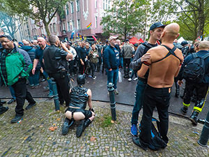 Two men kissing and one man playing a puppy next to his cigar-smoking owner on the street in Berlin, Germany, during Folsom Europe gay fetish festival, photo by Ivan Kralj