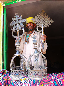 The monk at Abba Pentalewon monastery in Askum, Ethiopia, displaying ceremonial crosses and crowns of the King Kaleb and his son Gebre Meskel, photo by Ivan Kralj