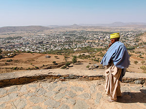 Monk of hilltop Abba Pentalewon monastery standing in front of the panorama of Aksum, Ethiopia, photo by Ivan Kralj