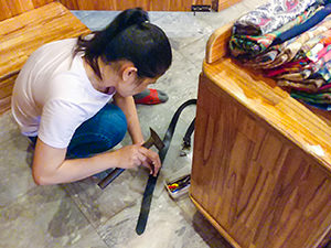 Shopkeeper making a hole in the belt with hammer and nail in Hoi An, Vietnam, photo by Ivan Kralj