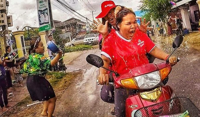Women on motorbike getting splashed with water during Songkran water festival for Khmer New Year in Battambang, Cambodia, photo by Ivan Kralj