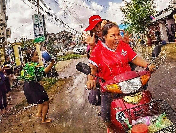 Women on motorbike getting splashed with water during Songkran water festival for Khmer New Year in Battambang, Cambodia, photo by Ivan Kralj