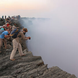 Visitors looking into and taking photographs at the edge of the smoke-filled crater at Erta Ale volcano in Danakil Depression, Ethiopia, the hottest place on Earth, photo by Ivan Kralj