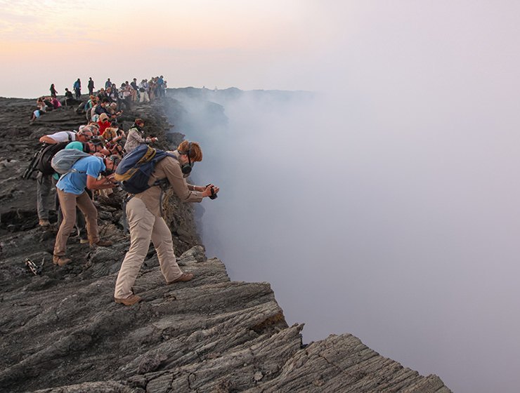 Visitors looking into and taking photographs at the edge of the smoke-filled crater at Erta Ale volcano in Danakil Depression, Ethiopia, the hottest place on Earth, photo by Ivan Kralj