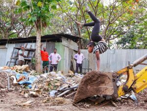 A girl contortionist from Arba Minch Circus performing a handstand on the excavator while surprised men are watching, Arba Minch, Ethiopia, photo by Ivan Kralj